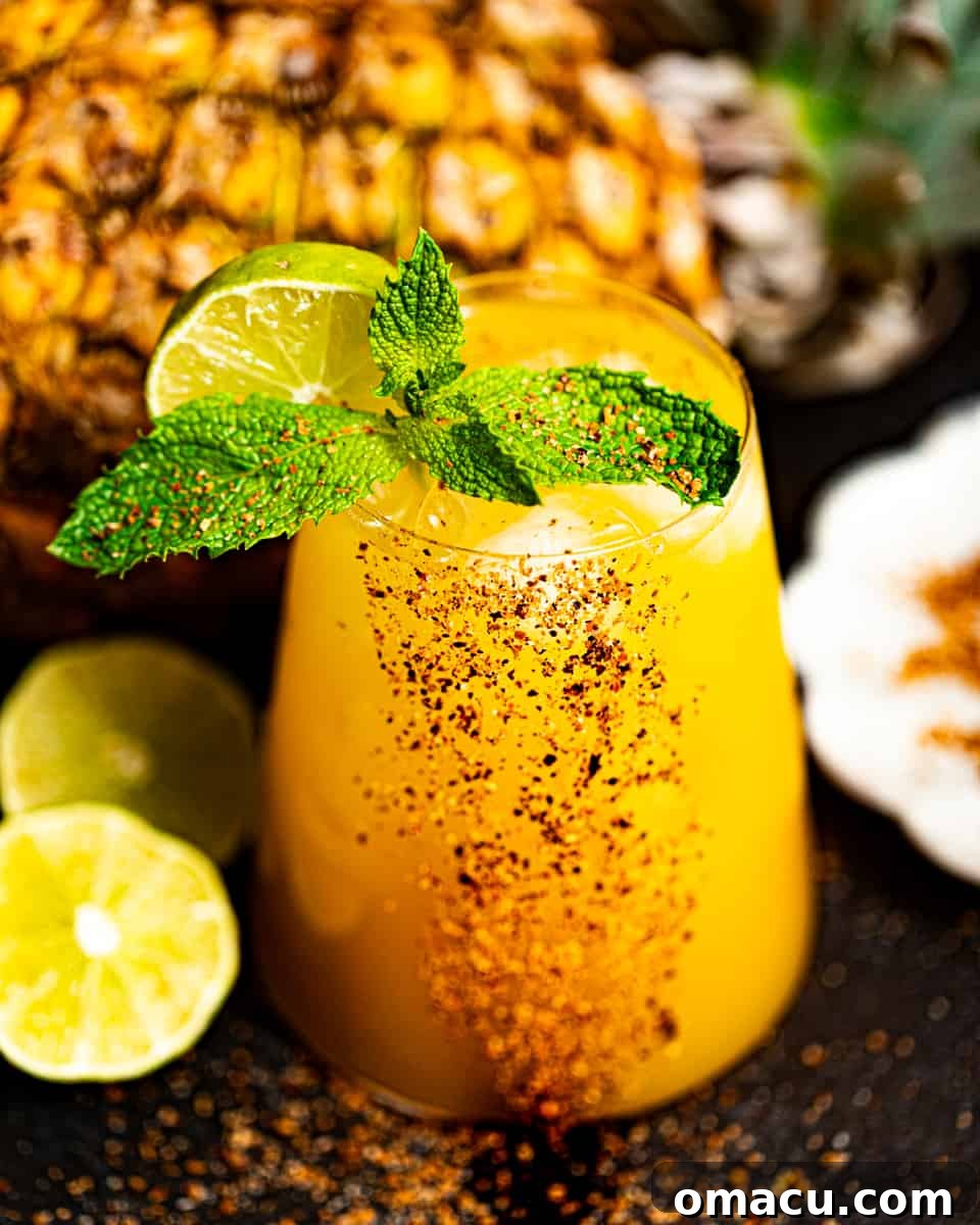 A mango tango drink in a cocktail glass garnished with fresh mint and a lime slice, evoking tropical vibes.