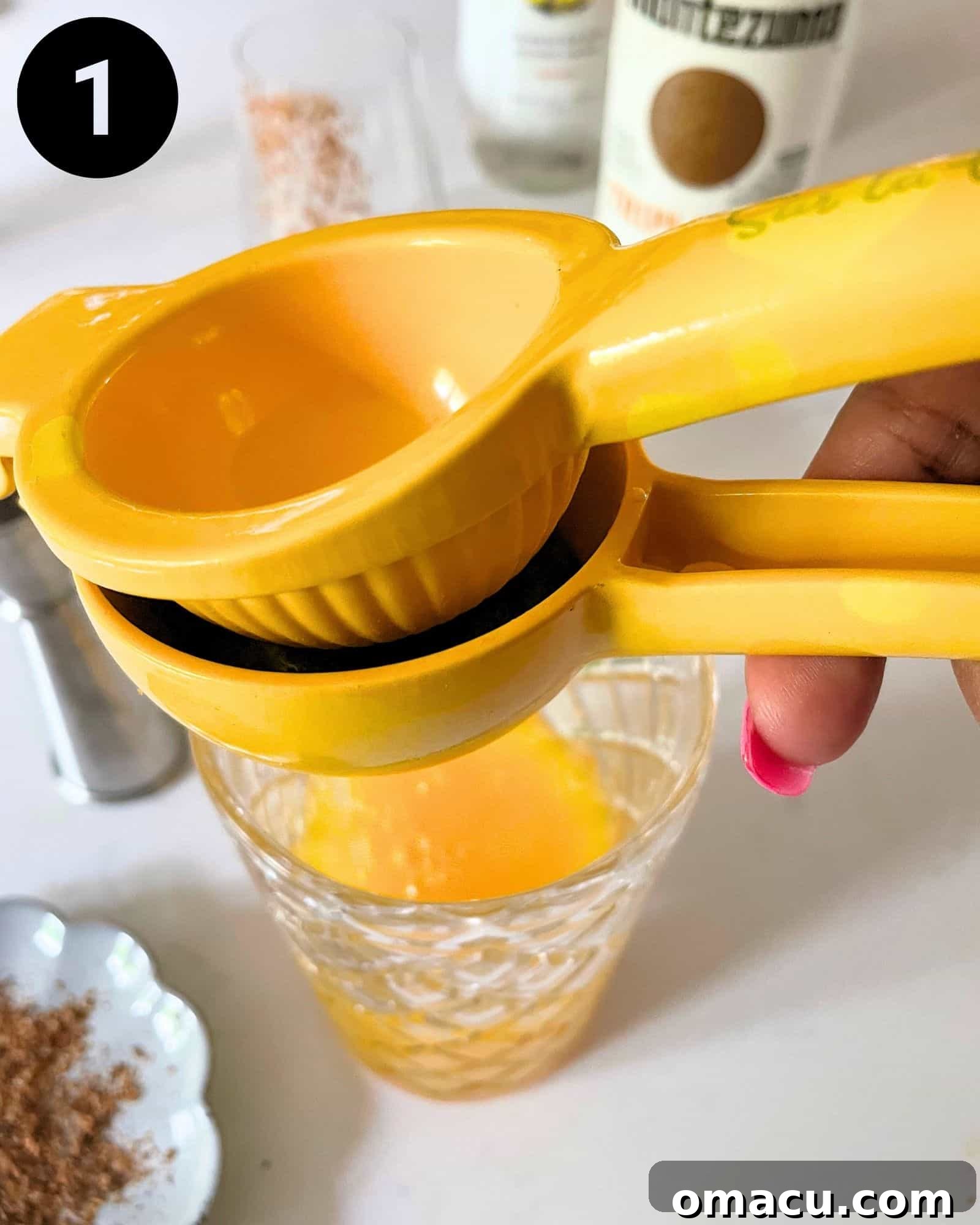 Squeezing fresh lime juice into a cocktail shaker filled with other mango tango ingredients and ice.