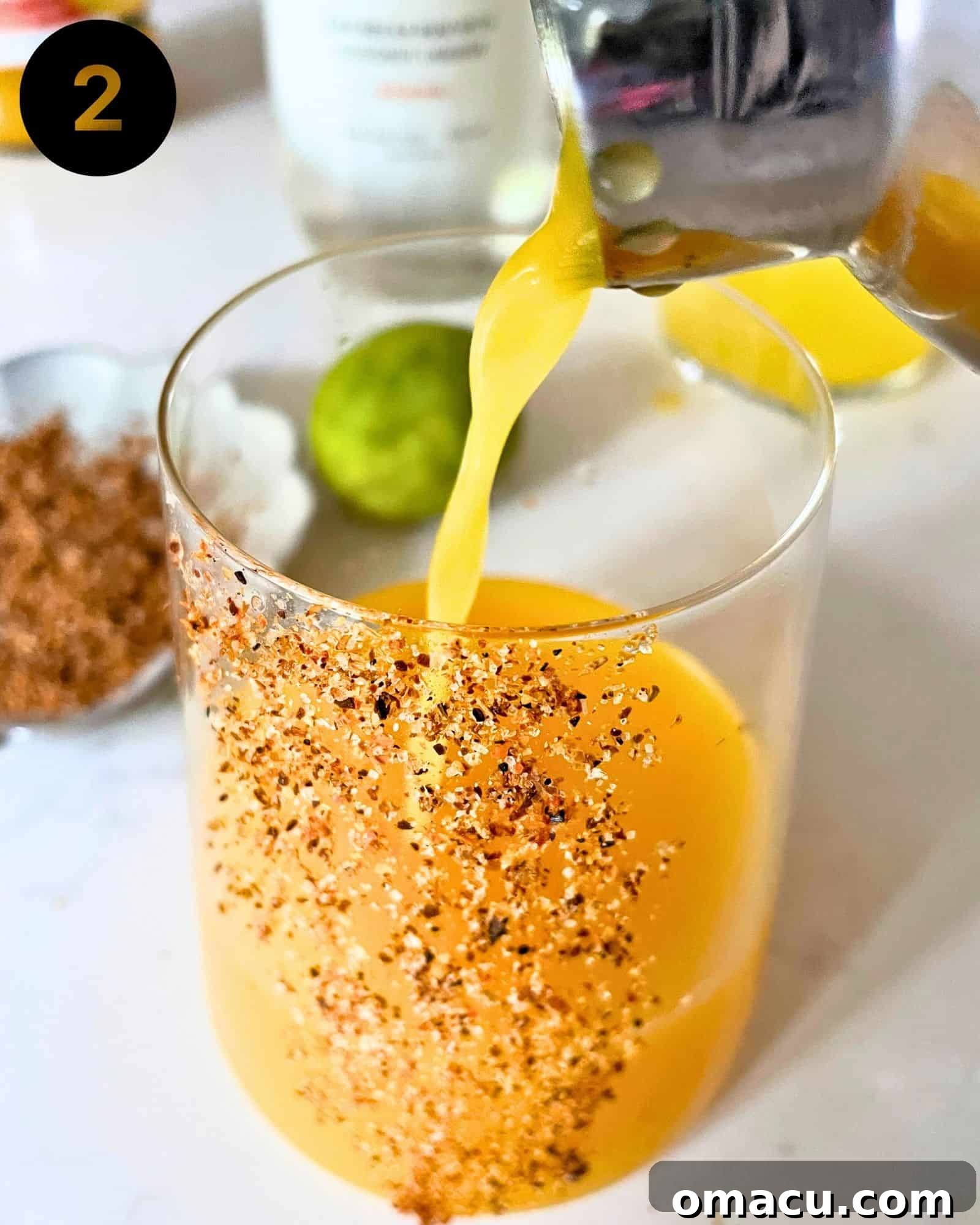 Pouring the perfectly shaken mango tango drink from the cocktail shaker into an elegant cocktail glass.