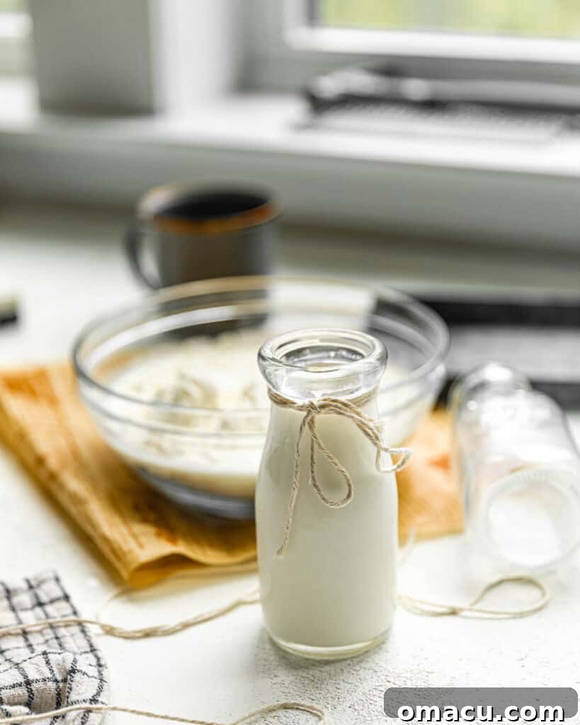 A kitchen counter showcasing baking ingredients: flour in a bowl alongside a glass of buttermilk, highlighting its role in culinary preparations.