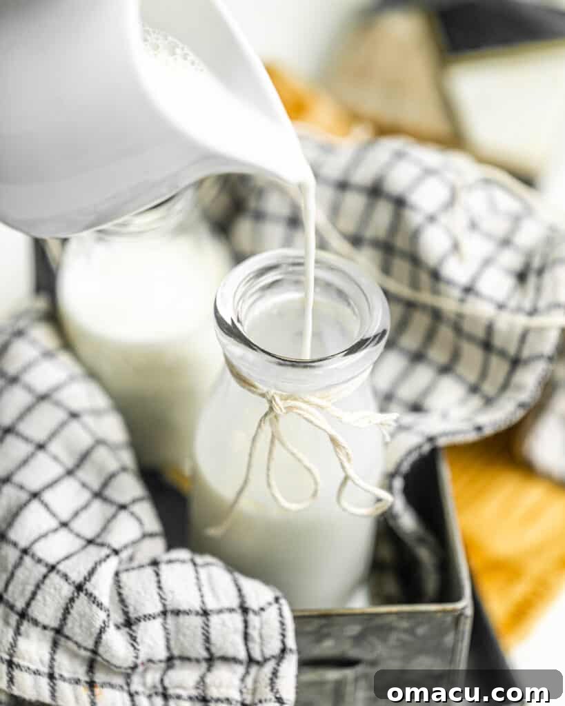 Pouring milk into a clear glass bottle, illustrating the first step in the homemade buttermilk preparation process.