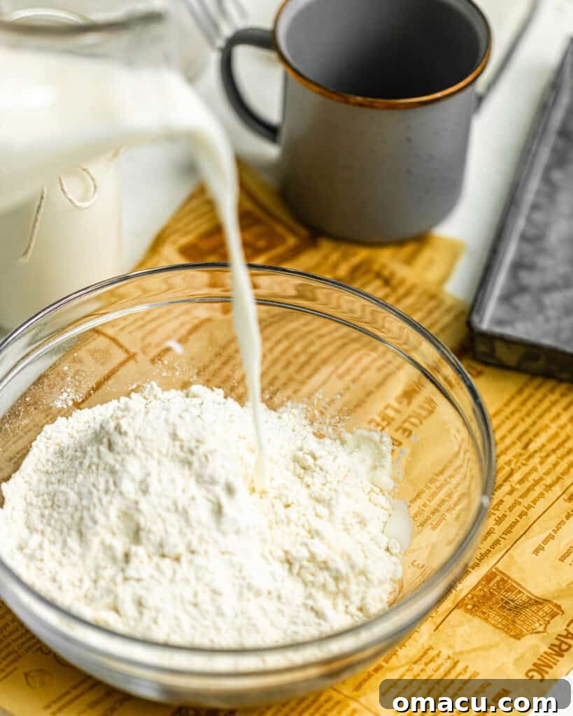 Homemade buttermilk being poured into a mixing bowl filled with flour, perfectly demonstrating its use in baking preparations.
