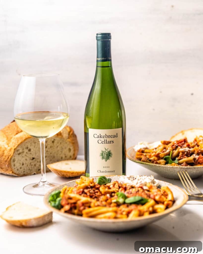 two bowls of pasta with a bottle of wine and a wine glass