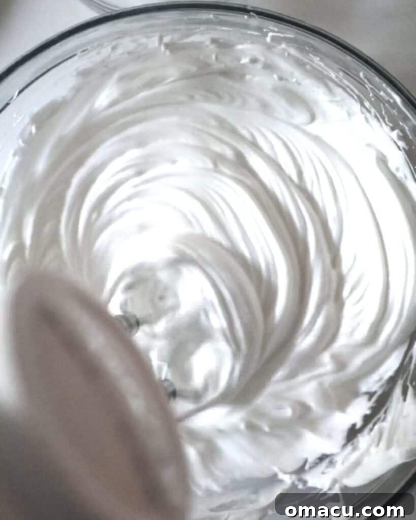 meringue in a bowl with a hand mixer