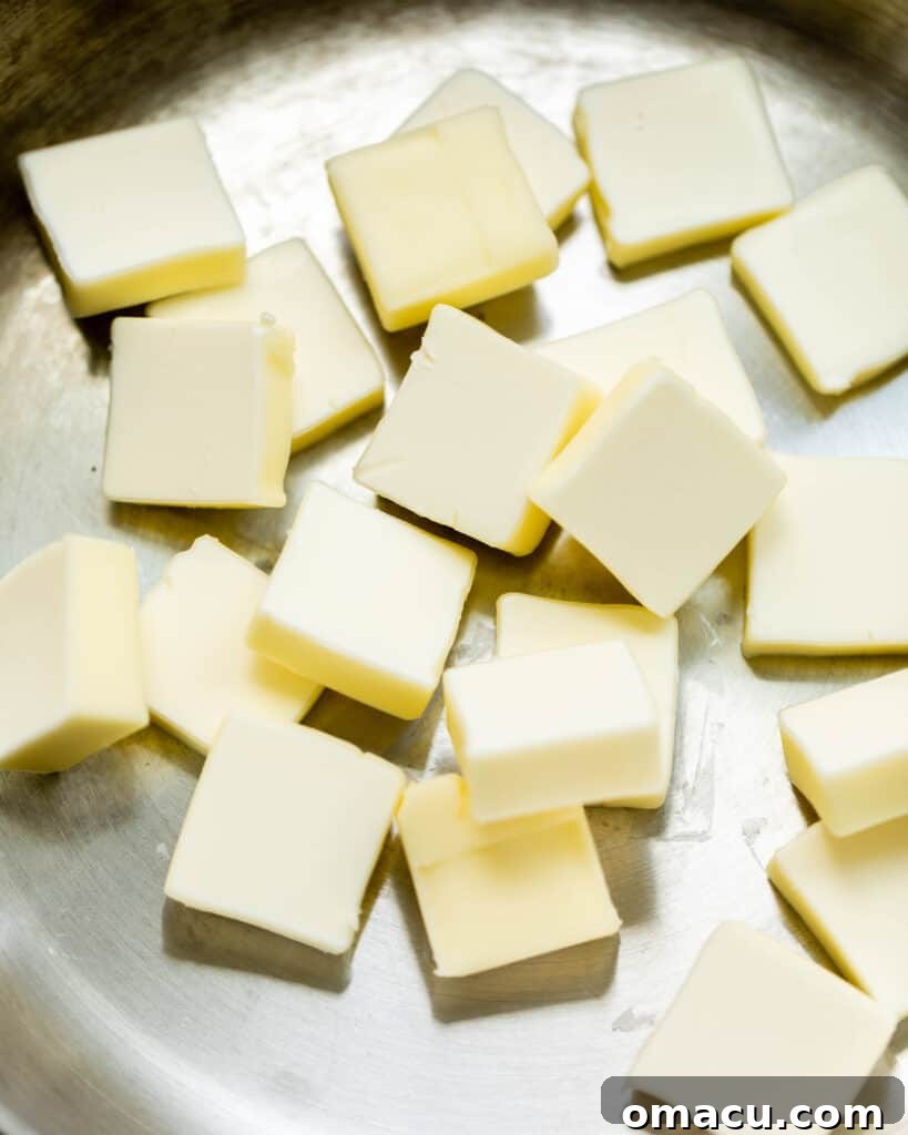 Fresh stick of butter, precisely sliced into even pieces, ready for the browning process.
