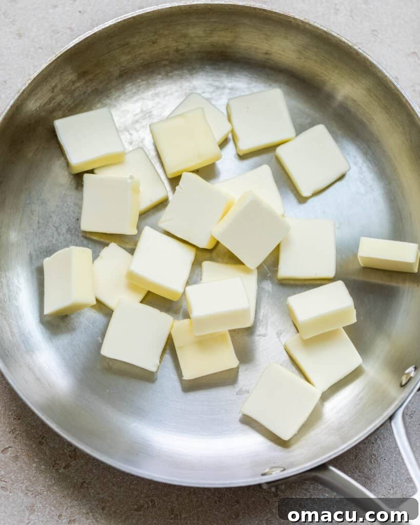 Butter sliced into small pieces, melting gently in a pan over low heat, beginning to bubble as water evaporates.