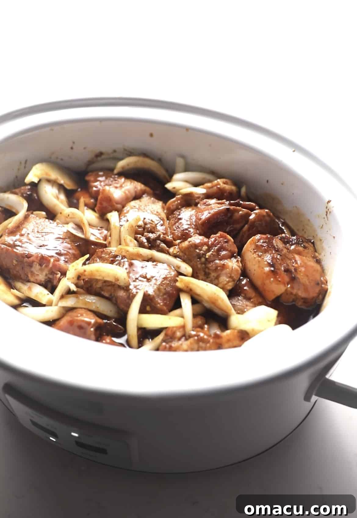 Succulent BBQ pulled pork cooking gently in a slow cooker, filling the kitchen with an inviting aroma.