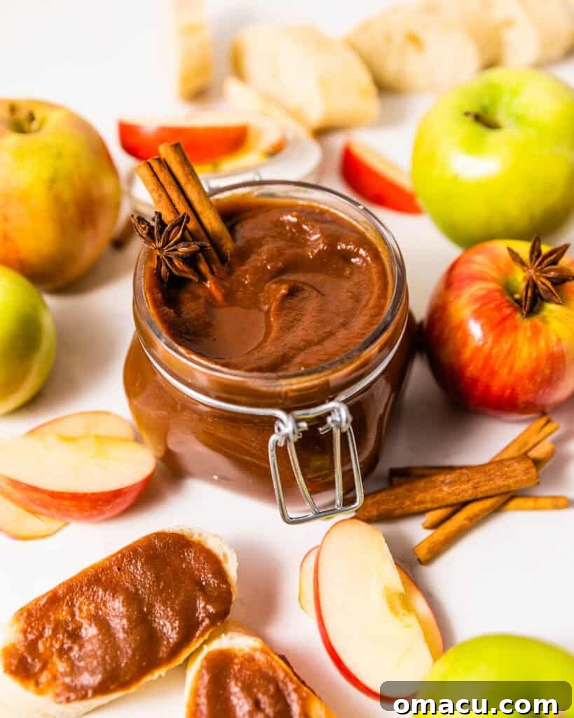 jarred apple butter surrounded by apples and cinnamon sticks