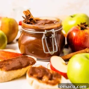 homemade apple butter in a jar surrounded by apples and toast