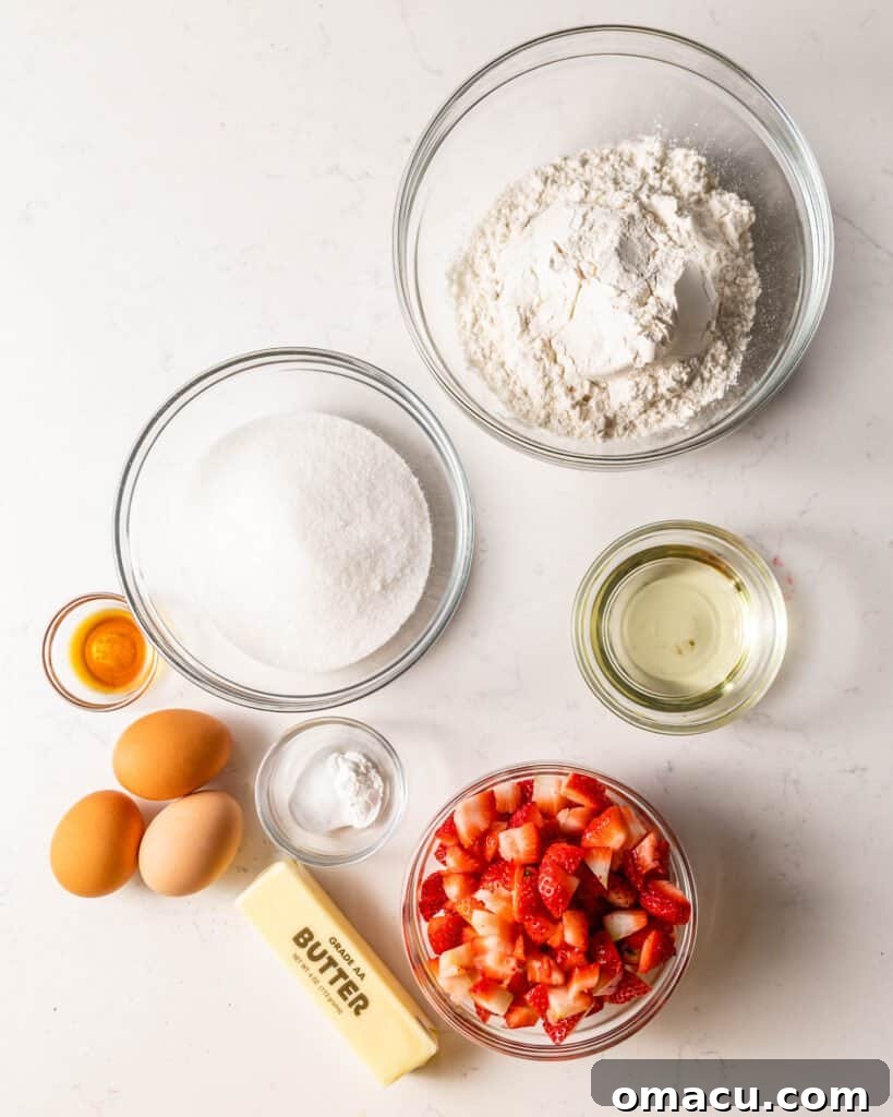 Various ingredients for strawberry bread laid out in bowls, including sliced strawberries, flour, sugar, and eggs, ready for mixing.