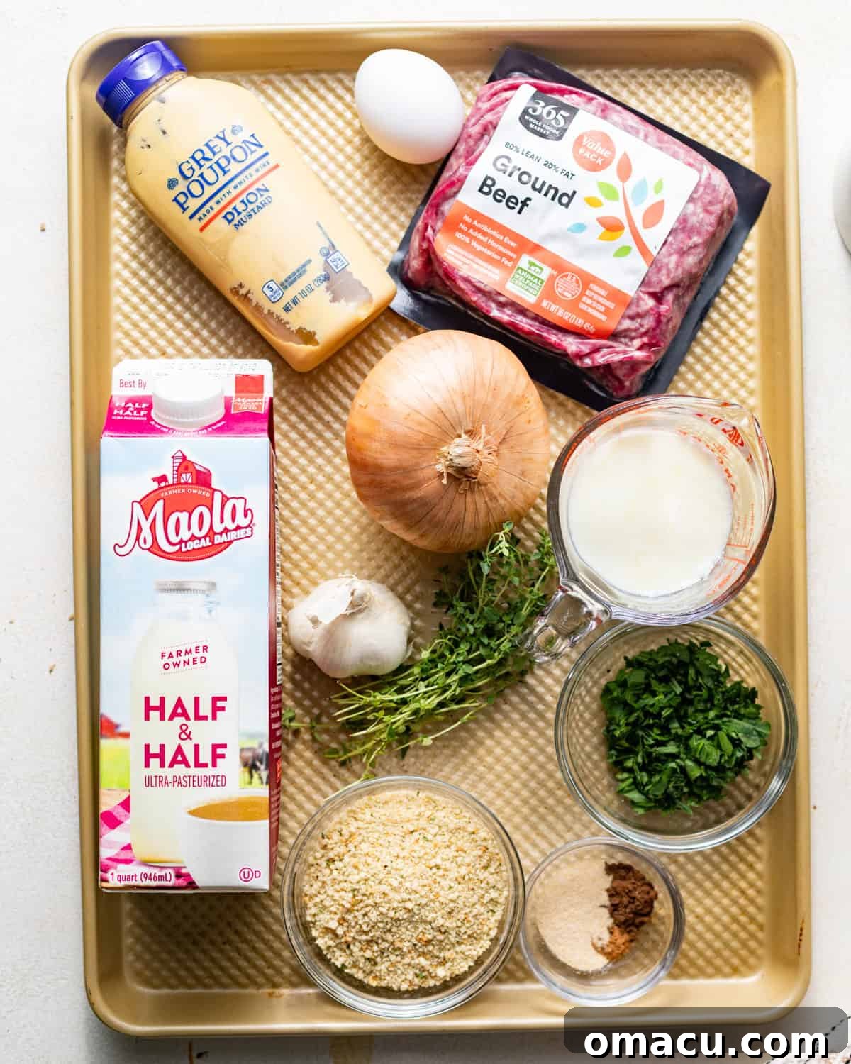 ingredients to make crock pot swedish meatballs on a baking tray - ground beef, onion, garlic, thyme, allspice, nutmeg, half and half, beef broth, cornstarch, dijon mustard, breadcrumbs, salt, pepper, and beef bouillon paste.