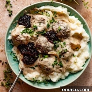crock pot swedish meatballs in a bowl with lingonberry jam and mashed potatoes.