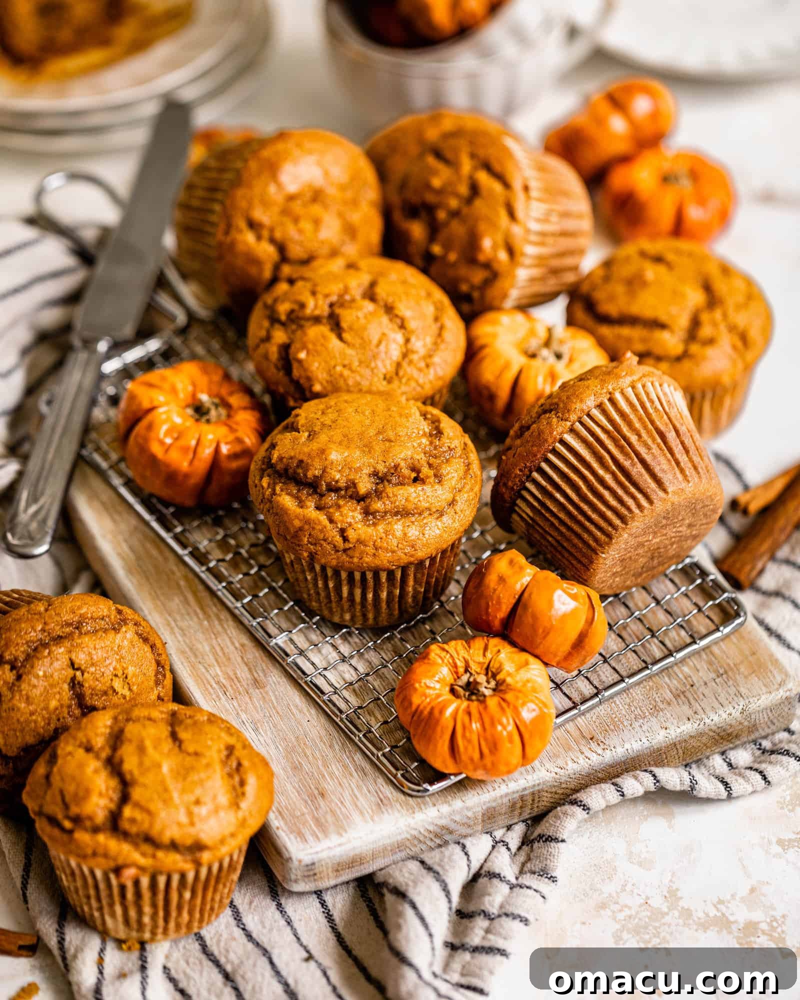 Multiple delicious pumpkin muffins arranged elegantly on a serving board, accompanied by small decorative pumpkins, perfect for a fall gathering.