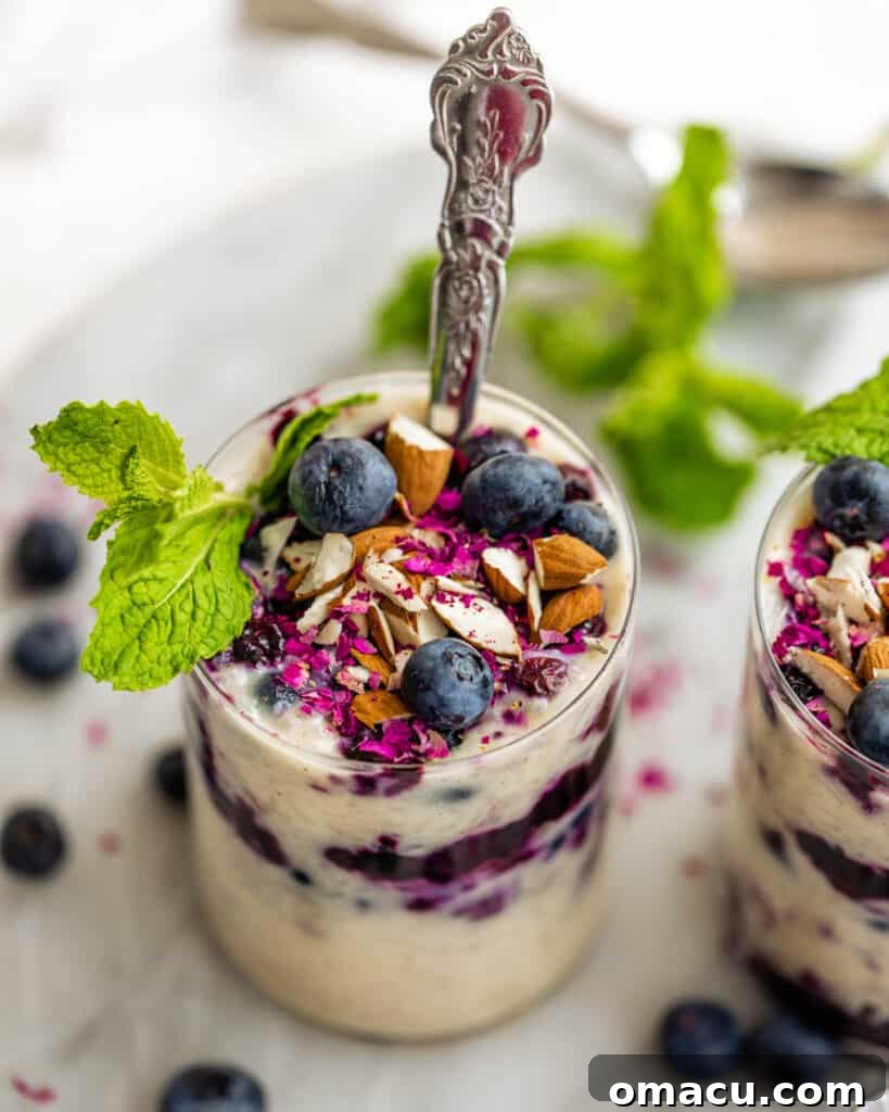 Individual cups of blueberry swirl rice pudding, some topped with toasted almonds and fresh blueberries, on a decorative serving tray.