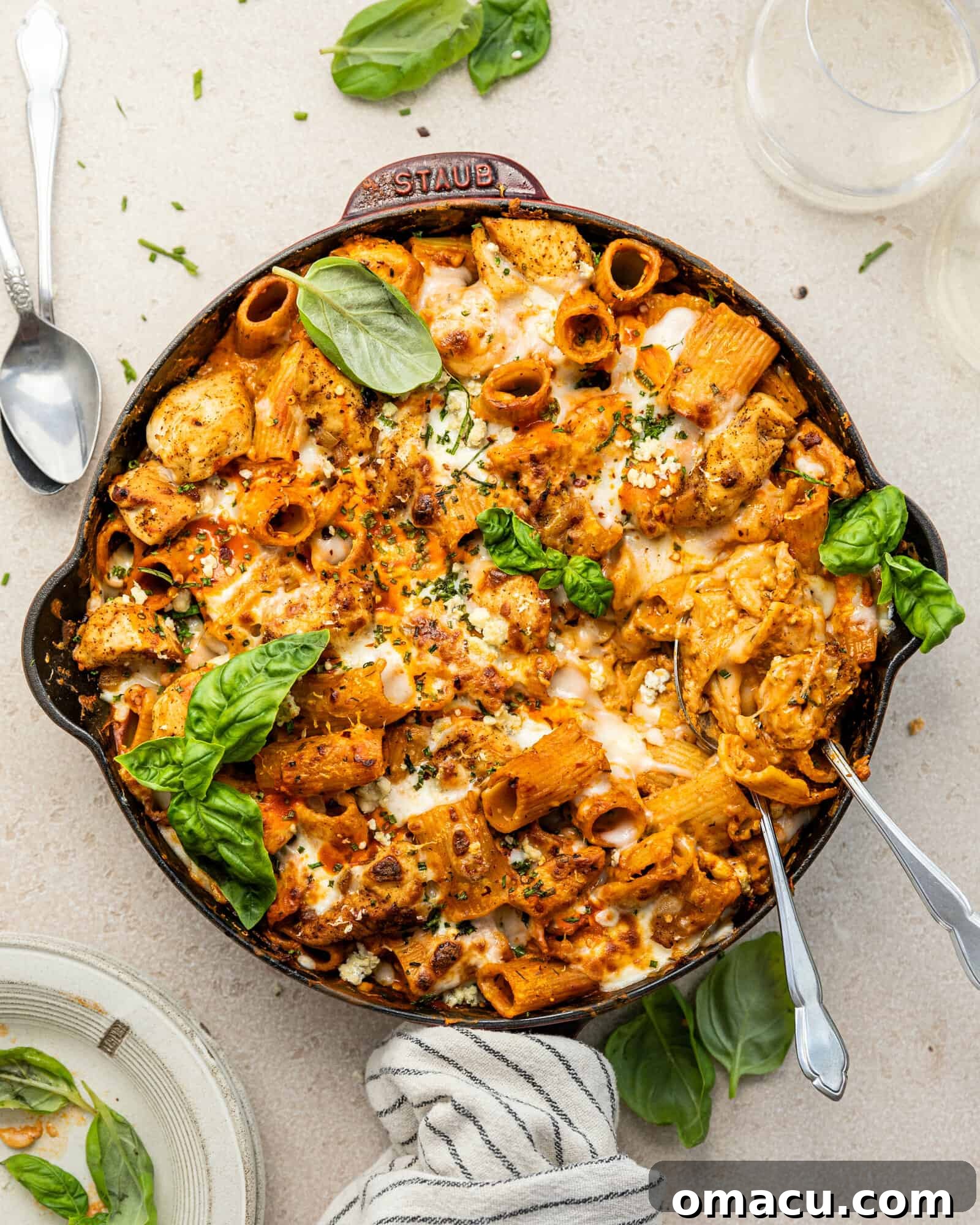 Large skillet filled with creamy buffalo chicken pasta, garnished with fresh basil leaves