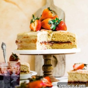 Strawberry Jam Cake on a cake stand topped with fresh strawberries, ready for a special occasion.