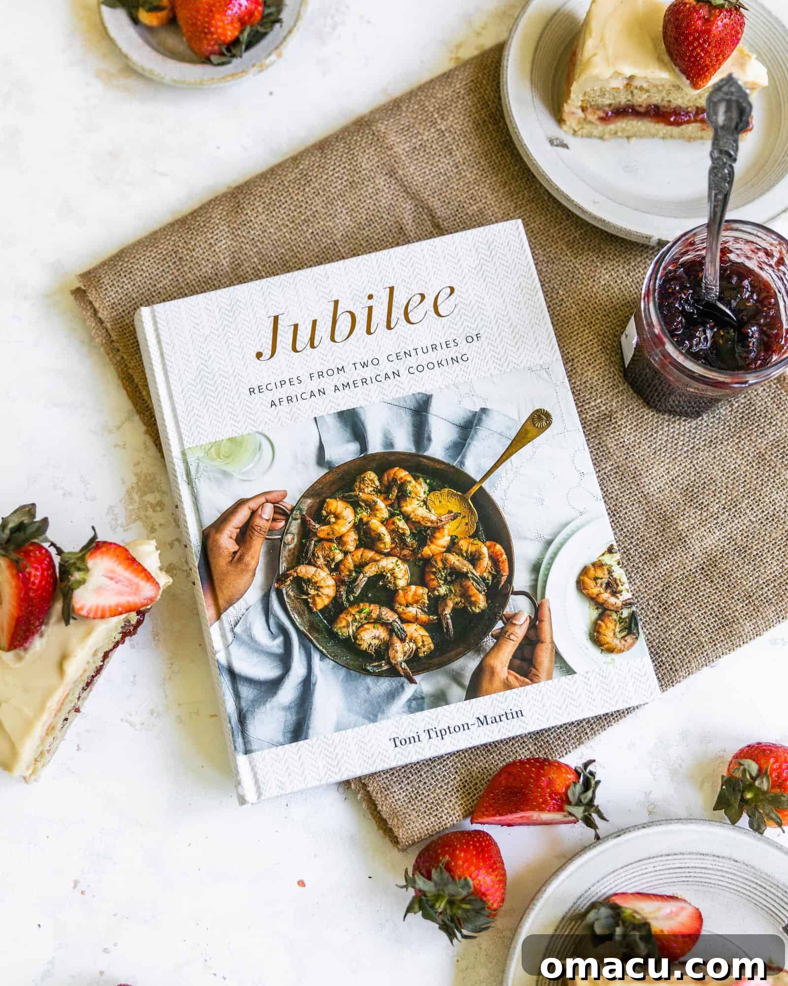 Toni Tipton-Martin's 'Jubilee' cookbook surrounded by slices of the delicious Jam Cake, illustrating culinary inspiration.