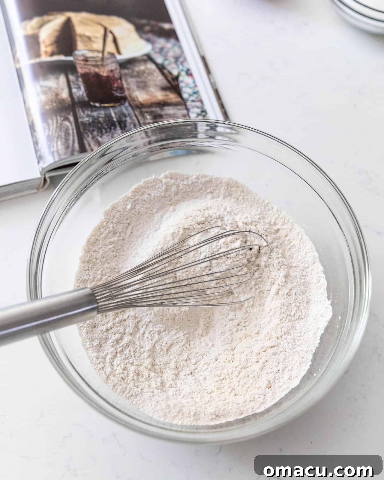 A close-up shot of dry ingredients being whisked together in a bowl, showing the preparation for the cake batter.