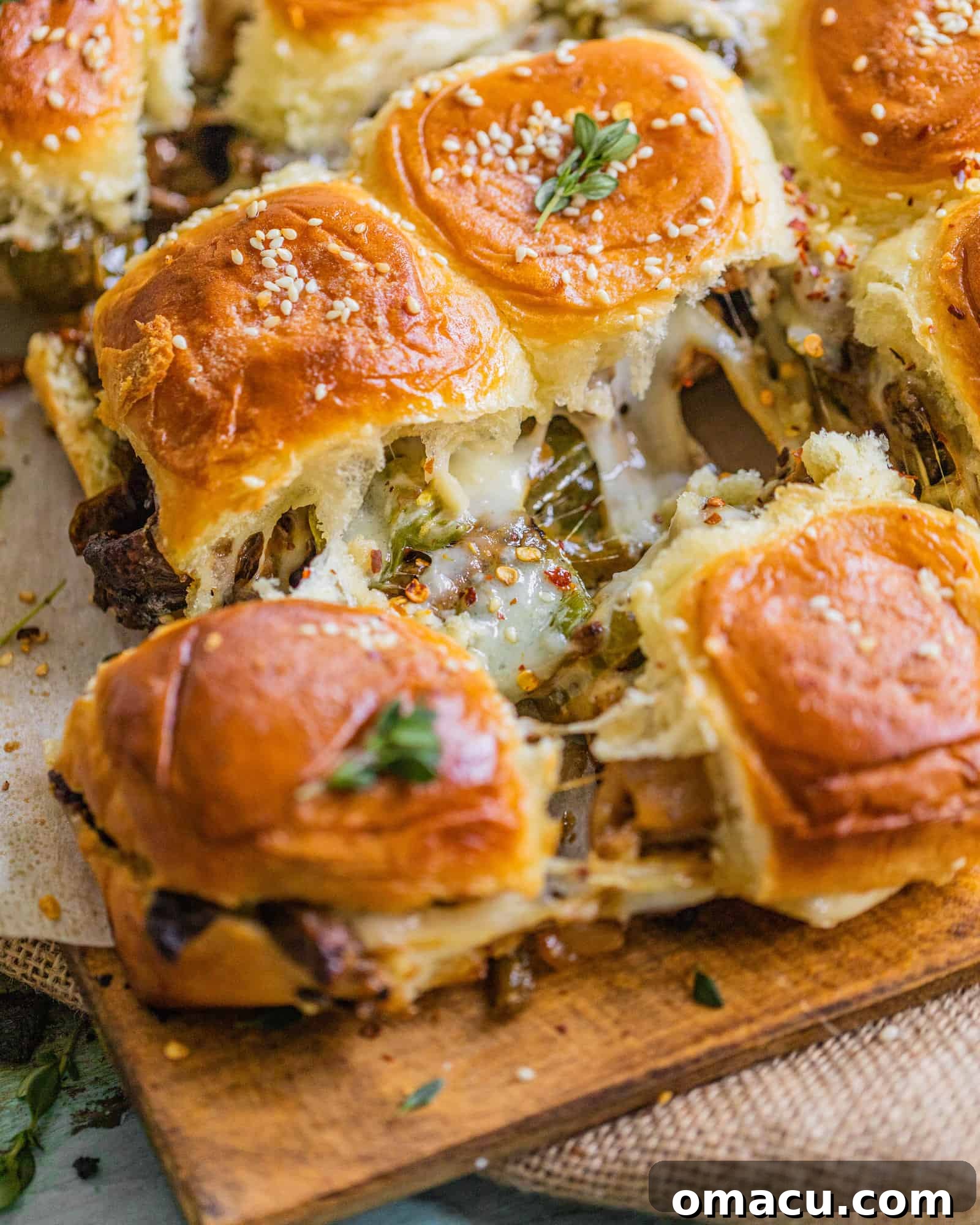 Close-up shot of sliders being pulled apart, showing melted cheese and steak