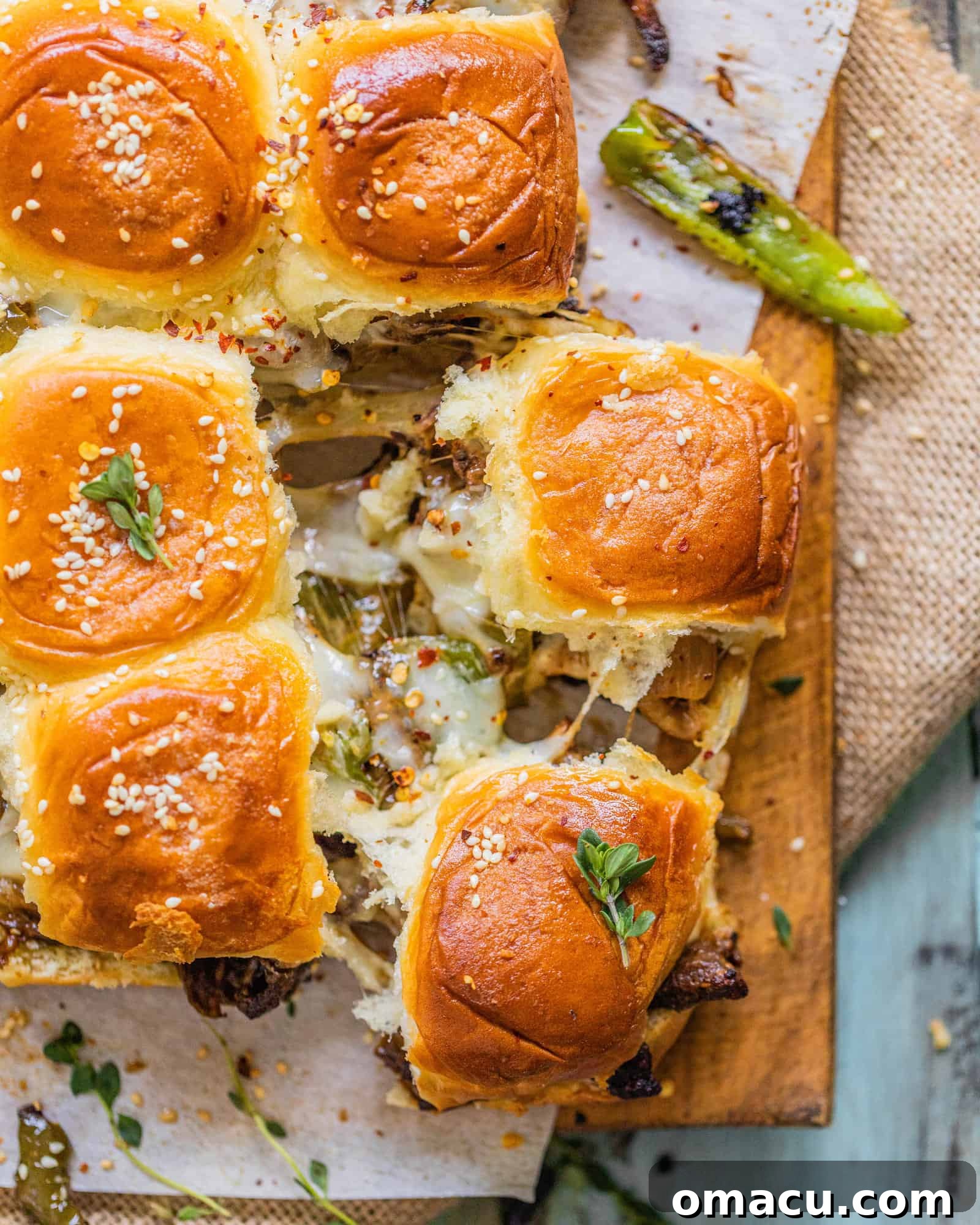 Two individual Philly Cheesesteak Sliders showing the filling of green peppers, onions, and melted cheese