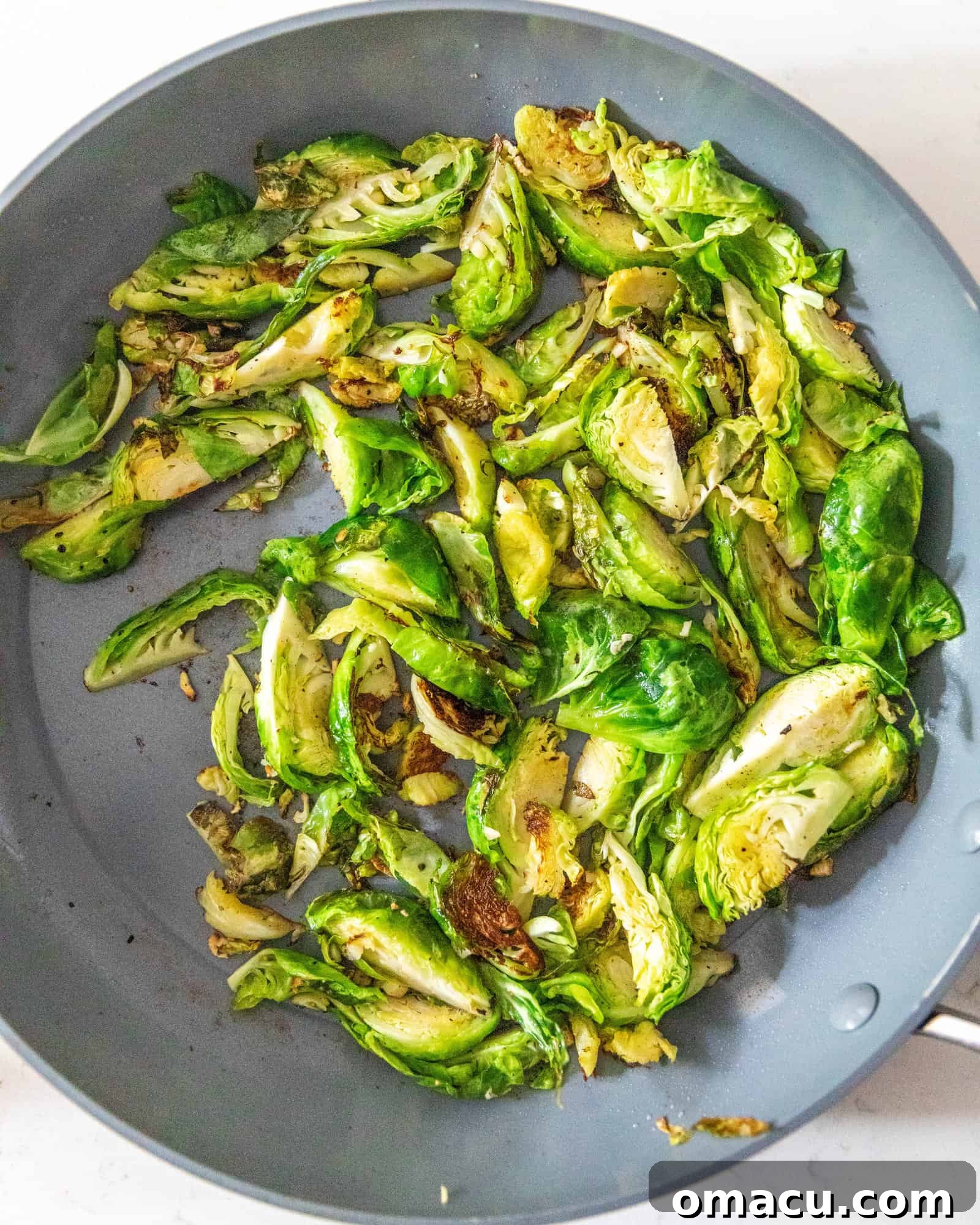 Brussels sprouts sizzling and browning in a hot frying pan, creating a delicious aroma.