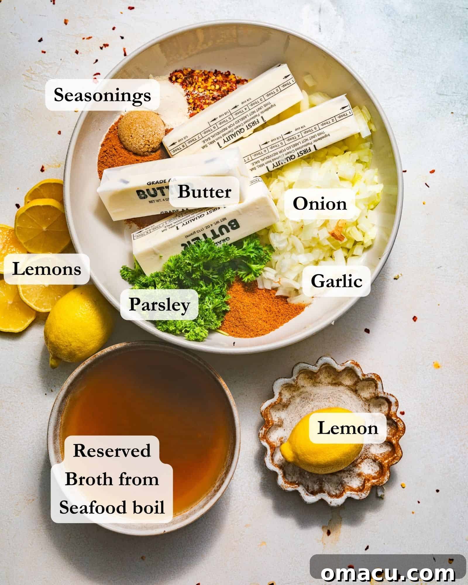 Ingredients for the rich garlic butter seafood boil sauce: melted butter, minced garlic, finely chopped onion, lemon slices, a selection of seasonings, fresh parsley, and a portion of the reserved seafood boil broth, all displayed on a white surface.
