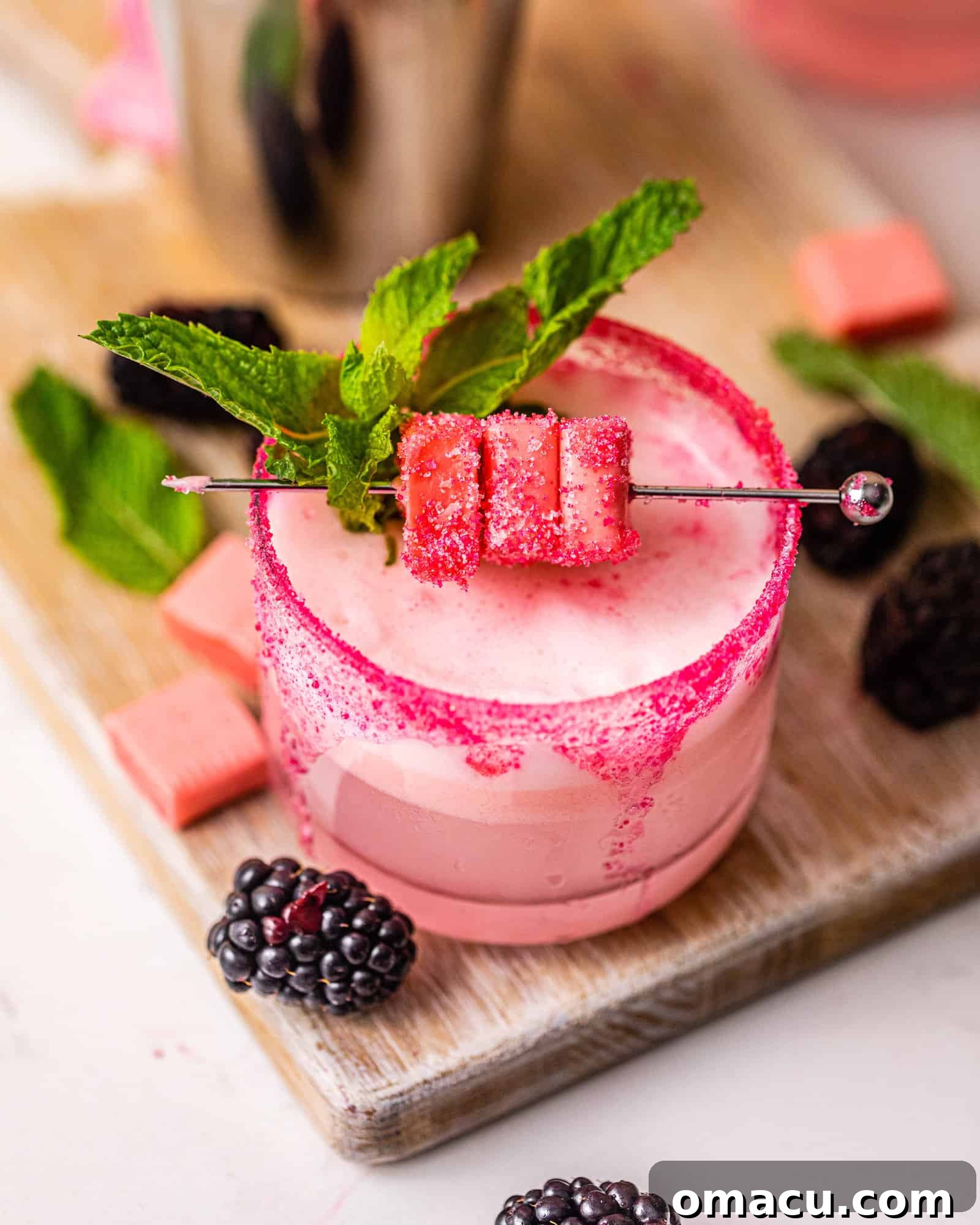 A vibrant pink Starburst drink presented on a serving board with fresh berries, highlighting its deliciousness.