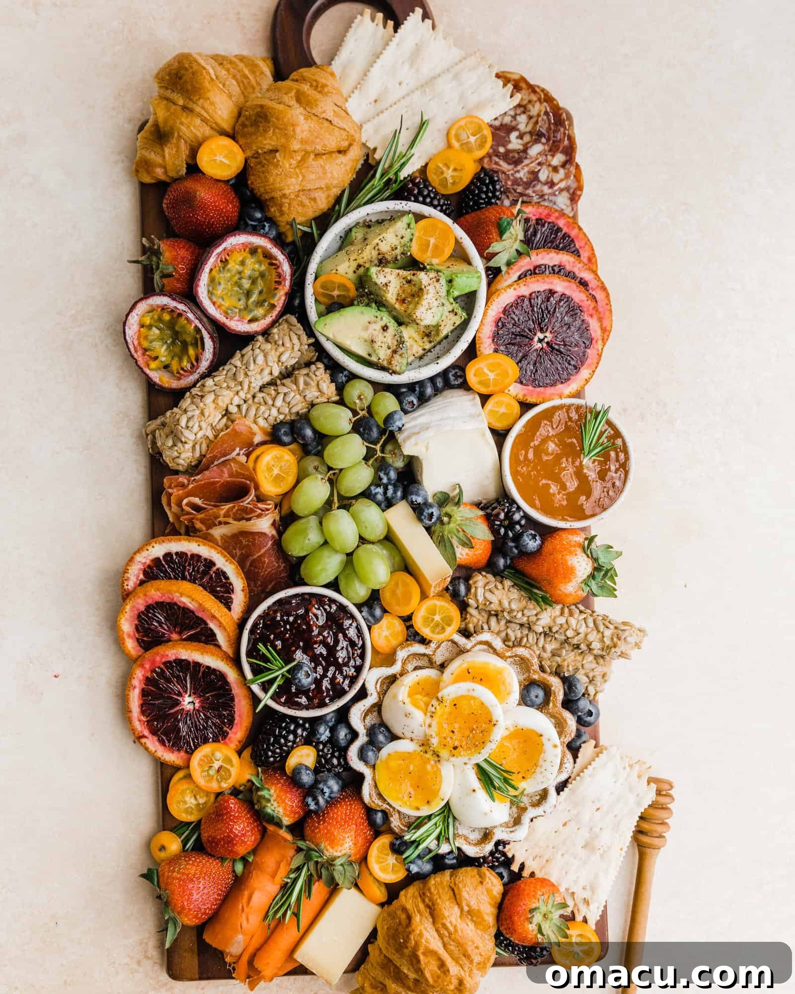A bountiful summer charcuterie board featuring fresh fruits, savory hard-boiled eggs, an assortment of meats, and freshly sliced bread on a rustic wooden board.