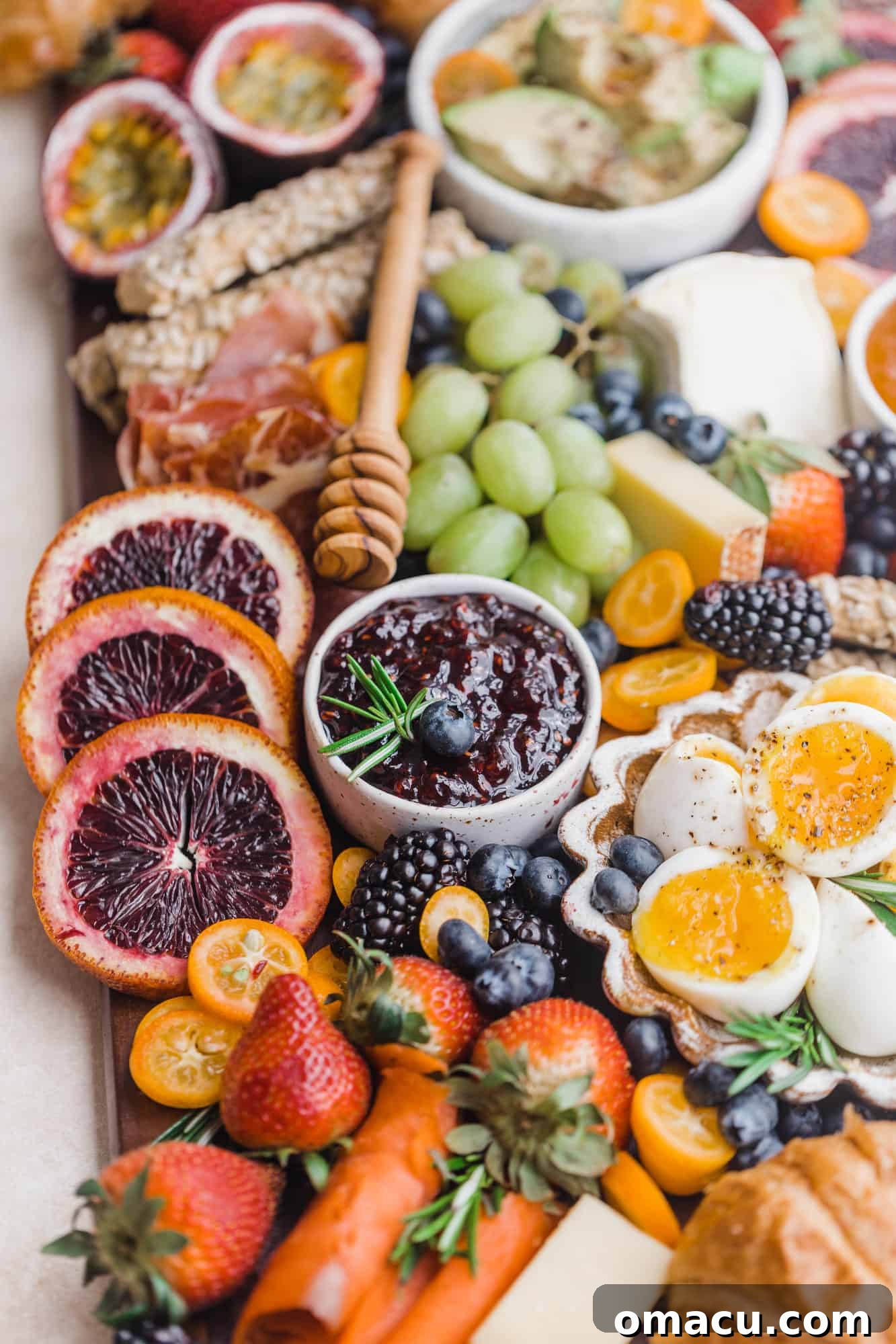 Close-up of a meticulously arranged charcuterie board featuring an array of gourmet meats, various cheeses, and vibrant fresh fruits, showcasing texture and color.
