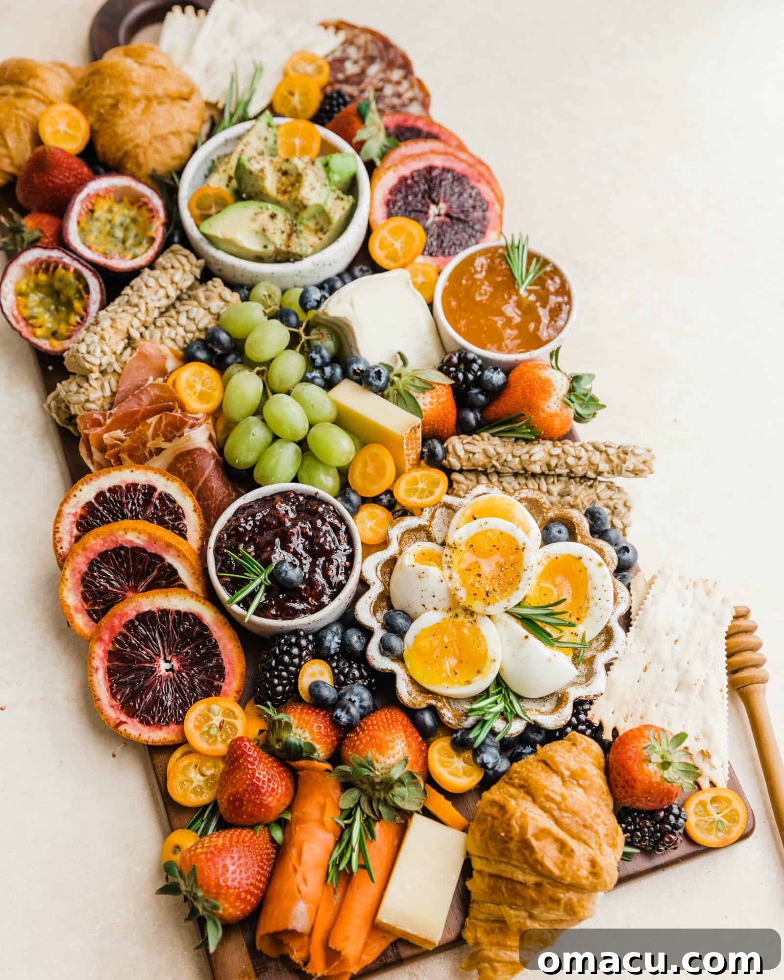 A beautifully assembled summer charcuterie board with seasonal produce, jellies, gourmet meats, and various breads, viewed from the side to show depth and variety.