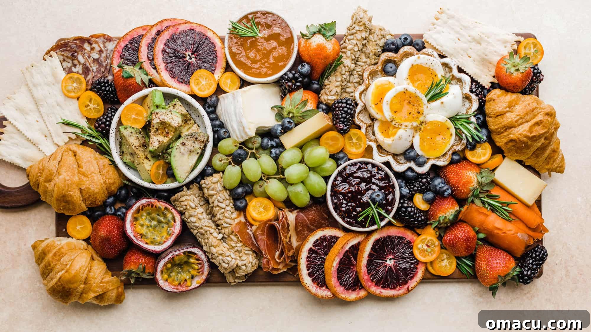 An expansive summer charcuterie board, fully assembled and artfully arranged on a chic pink surface, showcasing a vibrant display of ingredients.