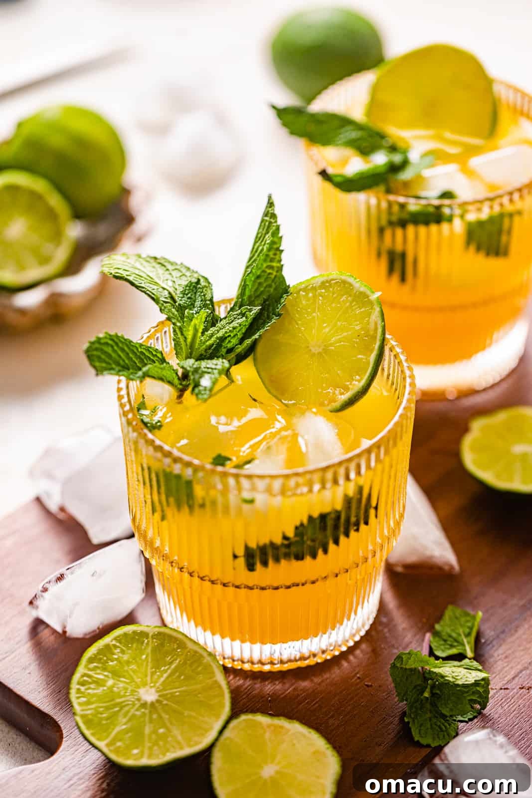 A glass of refreshing Mango Mojito garnished with mint leaves and a lime wedge, set against a bright background.