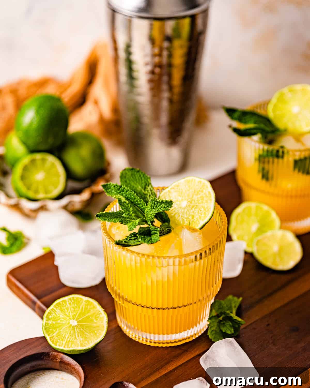 Two glasses of Mango Mojitos, garnished with fresh mango slices and mint, on a wooden surface.