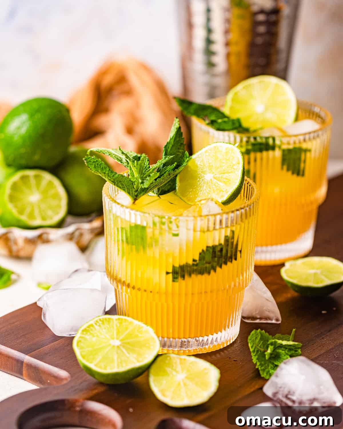 Mango Mojitos served on a brown tray, garnished with lime slices and mint, with ice cubes.