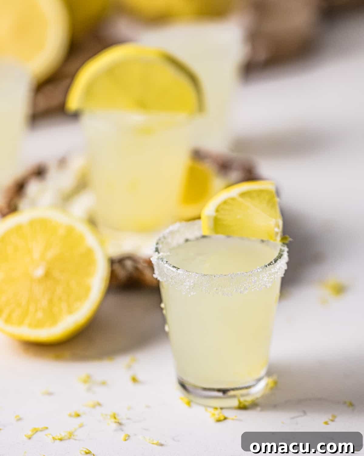 Multiple lemon drop shots arranged neatly on a white table, showcasing their bright color and sugared rims.