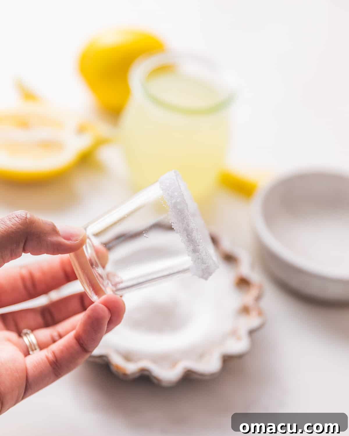 A shot glass with a perfectly coated sugar rim, glistening and ready for the drink.