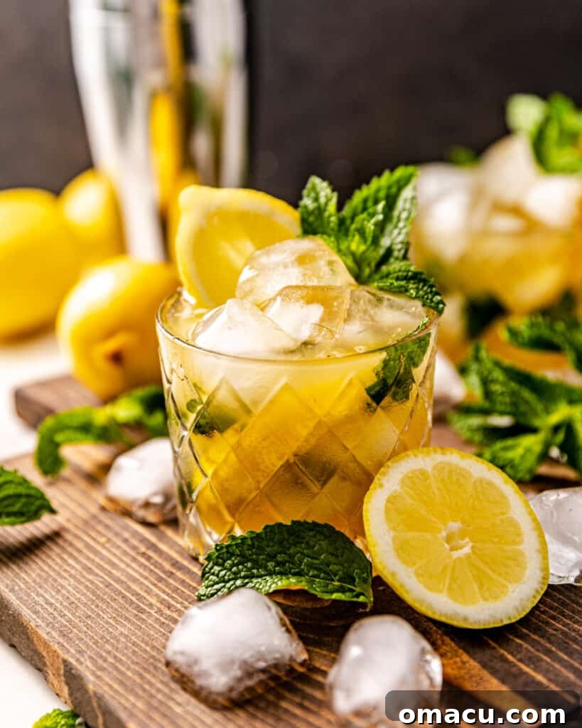 A refreshing Bourbon Smash cocktail artfully arranged on a rustic cutting board, surrounded by fresh lemons and glistening ice cubes, ready for serving.