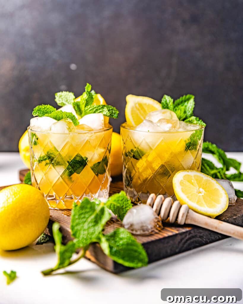 Two perfectly crafted Bourbon Smash cocktails, garnished with fresh mint and lemon, elegantly presented on a sleek serving board, inviting a shared moment.