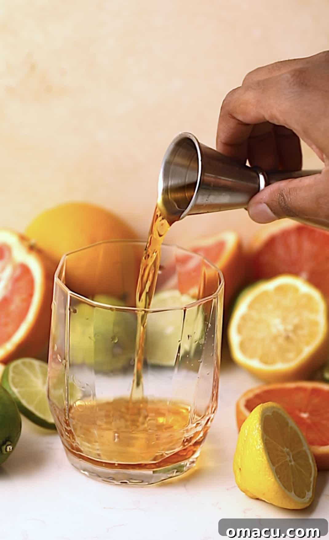 A hand expertly pouring dark rum into a cocktail glass, the liquid glistening against the light.