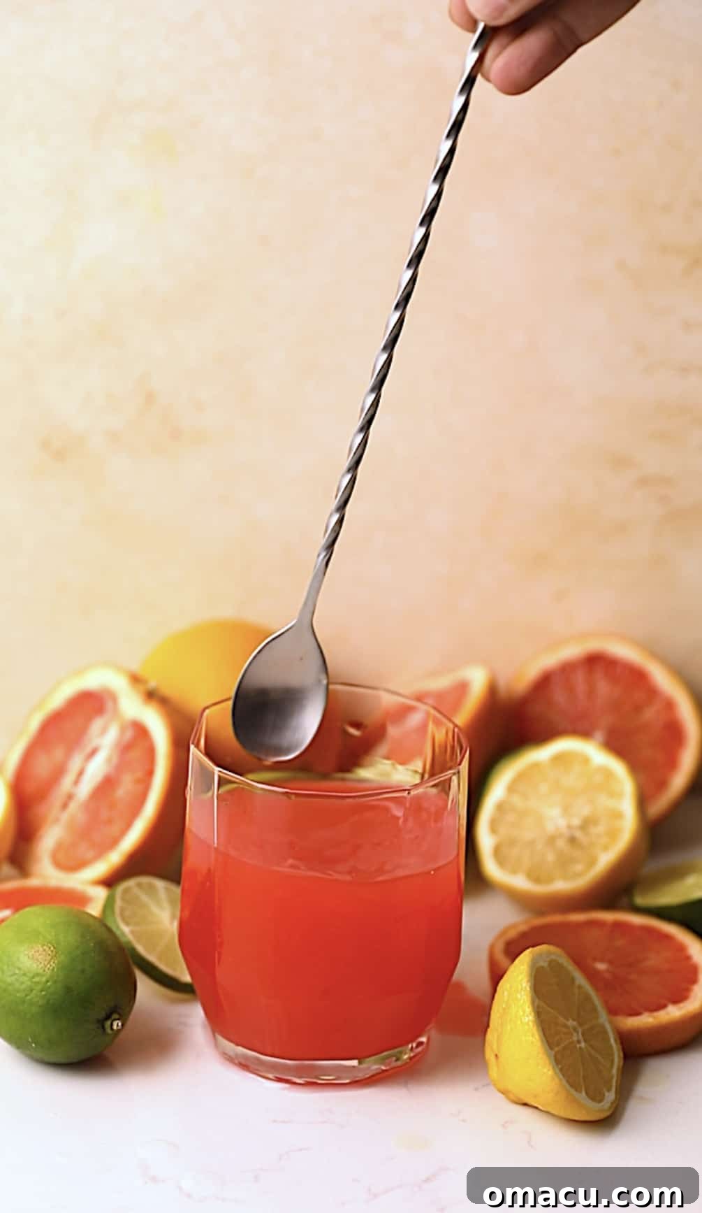 A cocktail stirrer gently mixing a Bahama Mama in a tall glass, blending the vibrant ingredients.