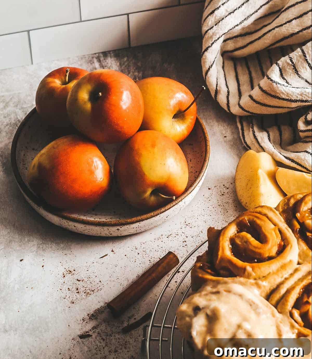 A whole pan of Apple Cider Cinnamon Rolls, generously frosted and garnished with a sprinkle of cinnamon.