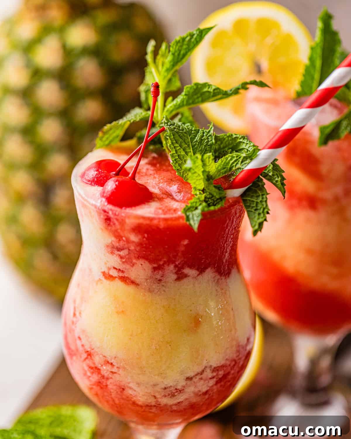 Close-up of a Miami Vice cocktail, garnished with maraschino cherries and a fresh lemon wedge, highlighting its vibrant layers.