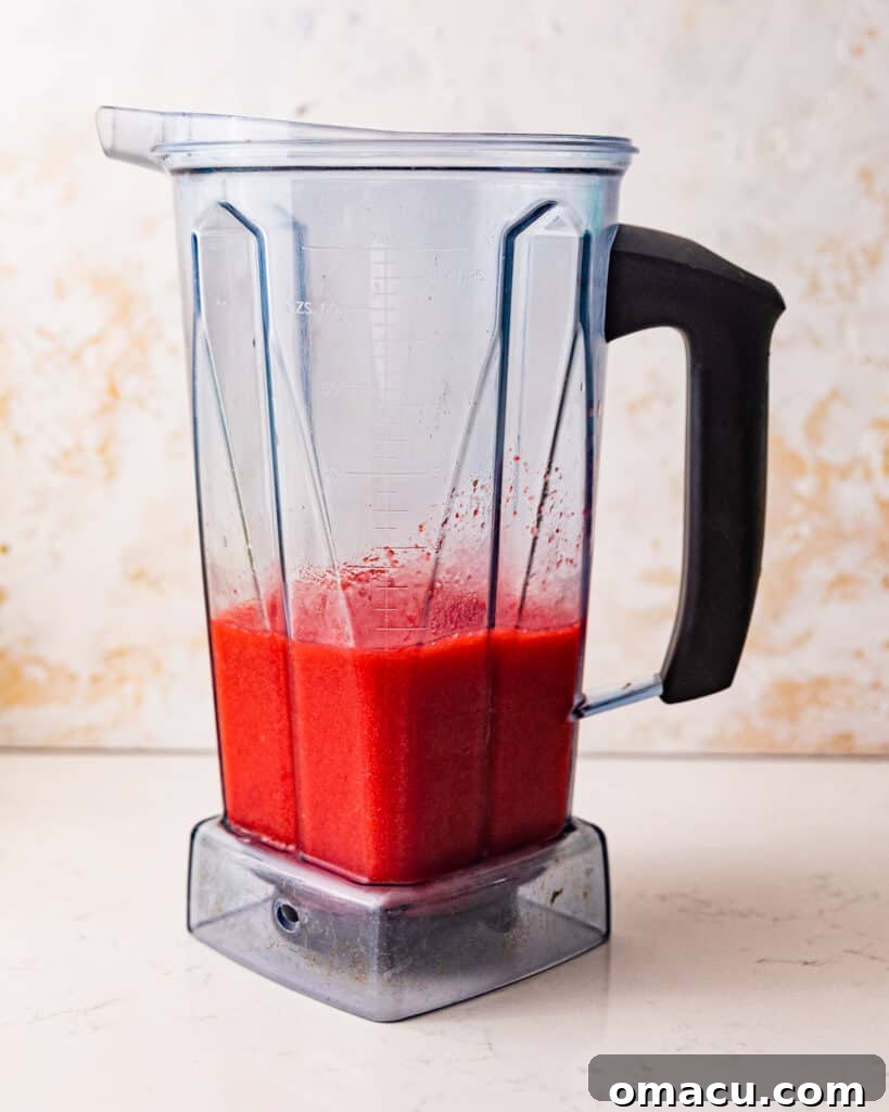 The vibrant red strawberry daiquiri layer blending smoothly in a high-speed blender, ready for the Miami Vice.