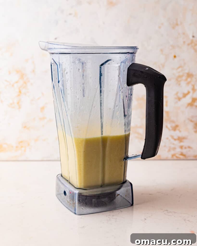 The creamy, white frozen piña colada layer being blended in a blender, preparing for its role in the Miami Vice cocktail.