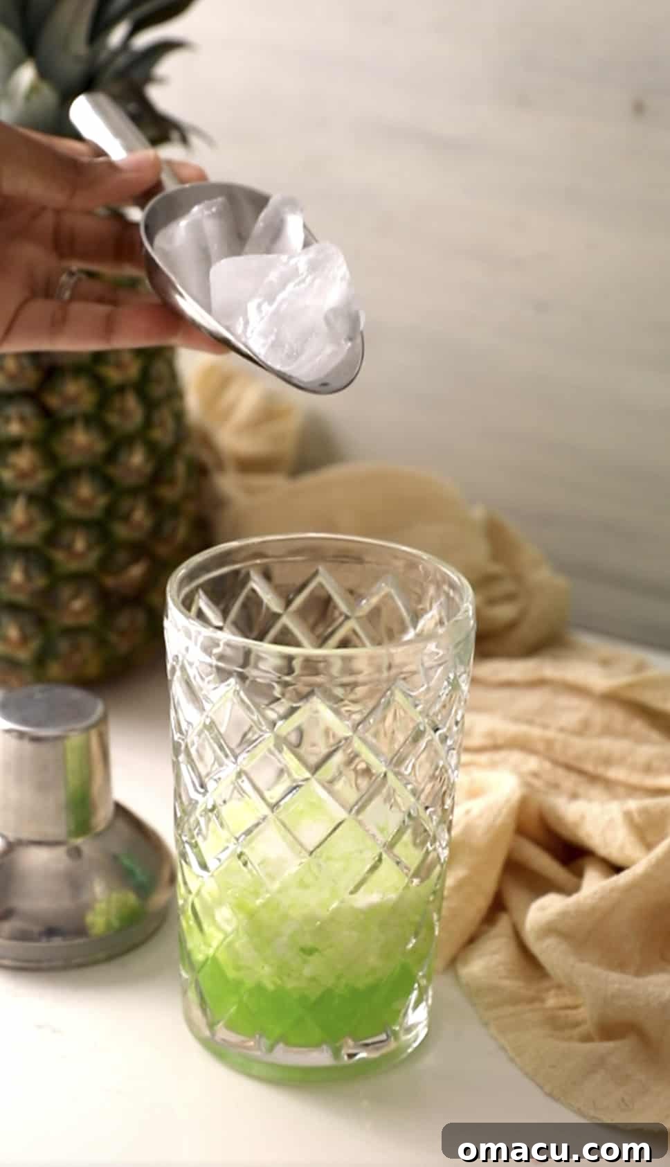 Ice cubes being dropped into the cocktail shaker, essential for chilling and proper mixing.