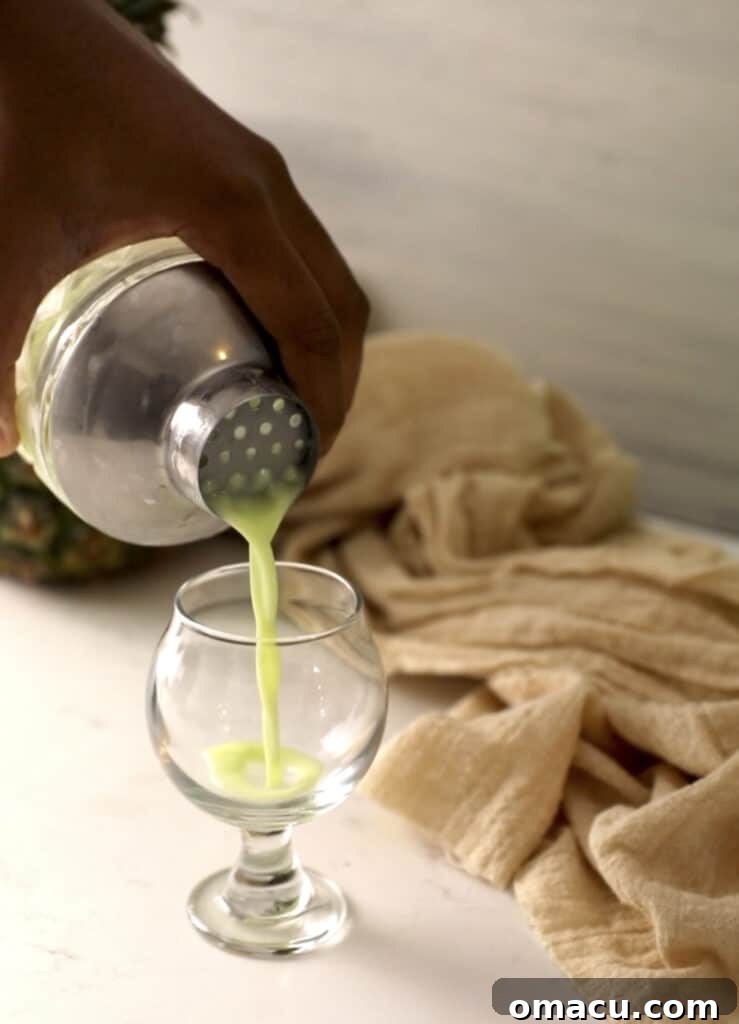 The finished Scooby Snack Shot being poured from the shaker into a shot glass, revealing its creamy green color.