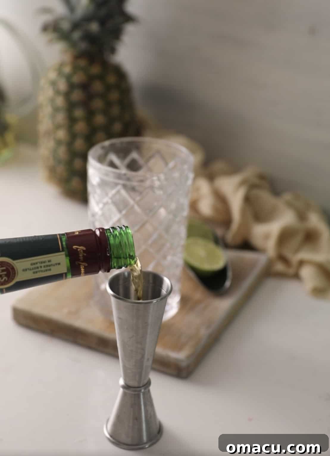 Pouring a measured amount of whiskey into a jigger, ensuring precise ingredient ratios for the shot.