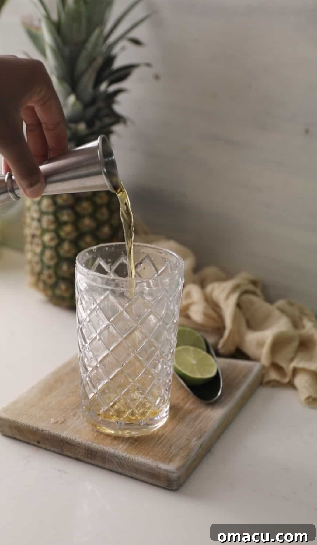 Whiskey being carefully poured from a jigger into a cocktail shaker, mixing with other ingredients.