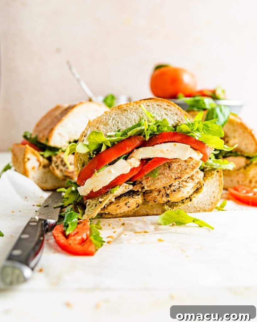 A perfectly cut chicken caprese sandwich, halved and presented invitingly, showcasing its delicious fillings.