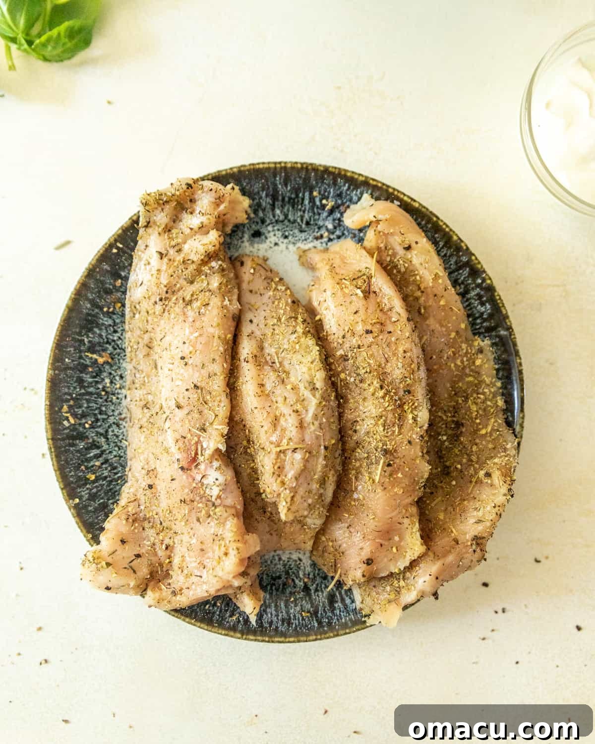 Seasoned chicken breasts neatly arranged on a plate, perfectly prepped and ready for cooking.